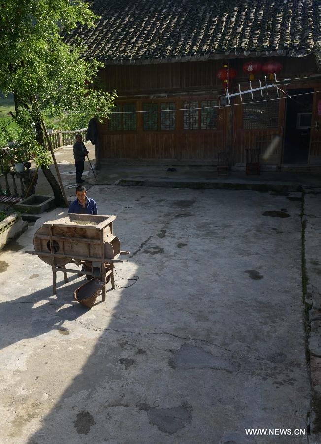 A villager named Zhang Xin'an eliminates dust using a winnower at Jinlongba Village in Enshi City, central China's Hubei Province, June 27, 2013. The Jinlongba Village was listed among the 646 Chinese Traditional Villages in 2012 and villagers here followed the traditional way of living. (Xinhua/Yang Shunpi)  