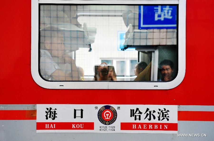 Passengers sit by the window of the train K1124 from northeast China's Harbin to south China's Haikou in Harbin, capital of northeast China's Heilongjiang Province, June 28, 2013. The train which travels 4,458 kilometers for 65 hours has connected China's northernmost capital city Harbin of Heilongjiang Province with southernmost capital city Haikou of Hainan Province. (Xinhua/Wang Jianwei) 