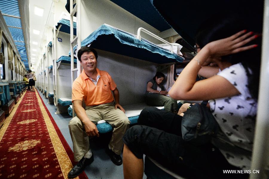 Passengers sit by the window of the train K1124 from northeast China's Harbin to south China's Haikou in Harbin, capital of northeast China's Heilongjiang Province, June 28, 2013. The train which travels 4,458 kilometers for 65 hours has connected China's northernmost capital city Harbin of Heilongjiang Province with southernmost capital city Haikou of Hainan Province. (Xinhua/Wang Kai) 