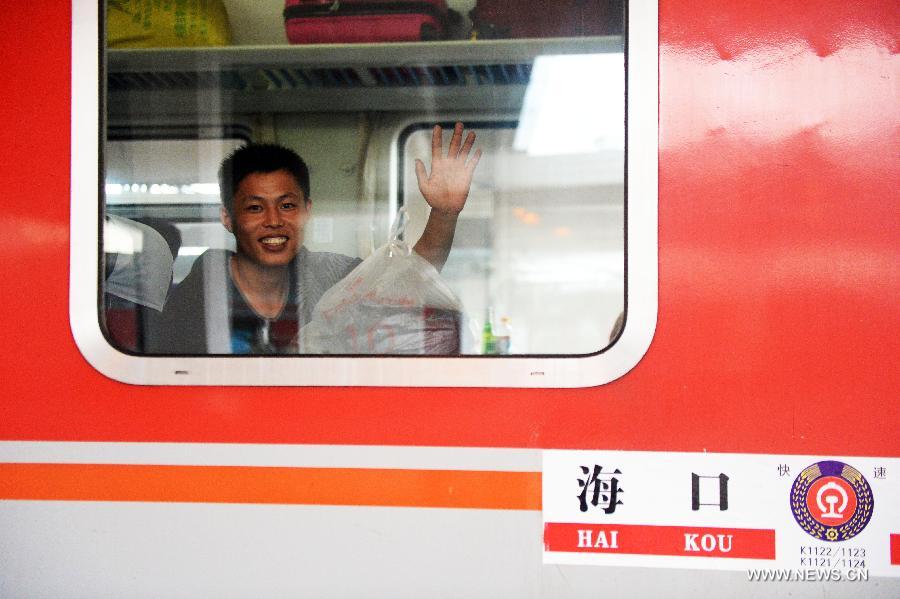 A passenger waves his hand in the train K1124 from northeast China's Harbin to south China's Haikou in Harbin, capital of northeast China's Heilongjiang Province, June 28, 2013. The train which travels 4,458 kilometers for 65 hours has connected China's northernmost capital city Harbin of Heilongjiang Province with southernmost capital city Haikou of Hainan Province. (Xinhua/Wang Kai) 