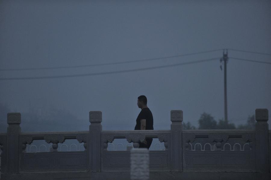 A man walks across Yongdingmen bridge in haze in Beijing, capital of China, June 28, 2013. Most parts of Beijing are shrouded by severe haze on Friday. (Xinhua/Song Weiwei)