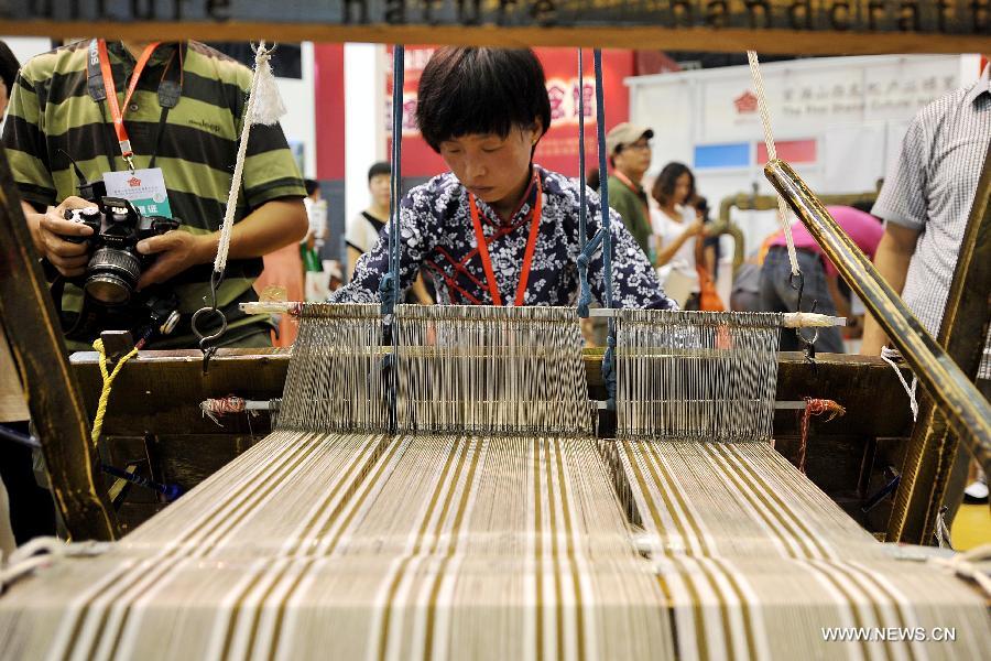A staff member demonstrates the traditional weaving techniques during the 1st Shanxi Cultural Industry Expo in Taiyuan, capital of north China's Shanxi Province, June 29, 2013. The exhibition will last till July 3. (Xinhua/Zhan Yan)