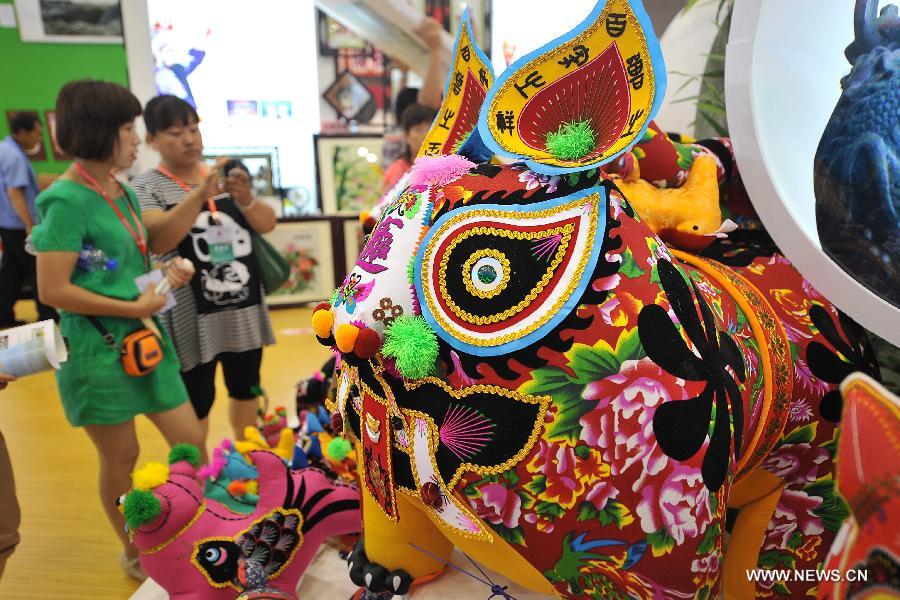 Visitors look at a cloth tiger during the 1st Shanxi Cultural Industry Expo in Taiyuan, capital of north China's Shanxi Province, June 29, 2013. The exhibition will last till July 3. (Xinhua/Zhan Yan)  