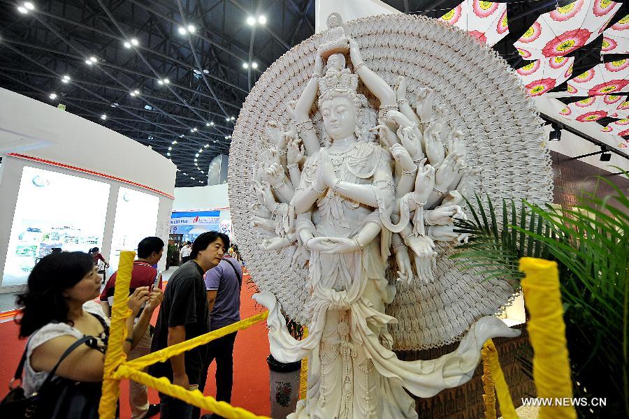 Visitors look at a statue of goddess Guanyin during the 1st Shanxi Cultural Industry Expo in Taiyuan, capital of north China's Shanxi Province, June 29, 2013. The exhibition will last till July 3. (Xinhua/Zhan Yan) 
