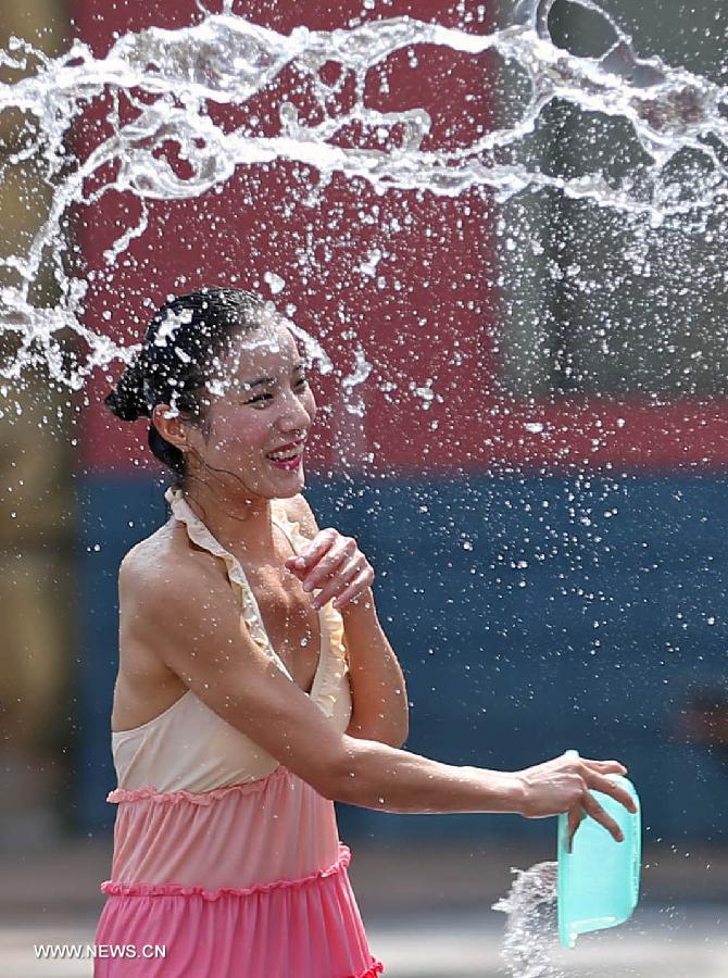 A woman plays in a water-splashing festival during the summer at the Colorful World in Changsha, capital of central China's Hunan Province, June 29, 2013. (Xinhua/Li Ga) 