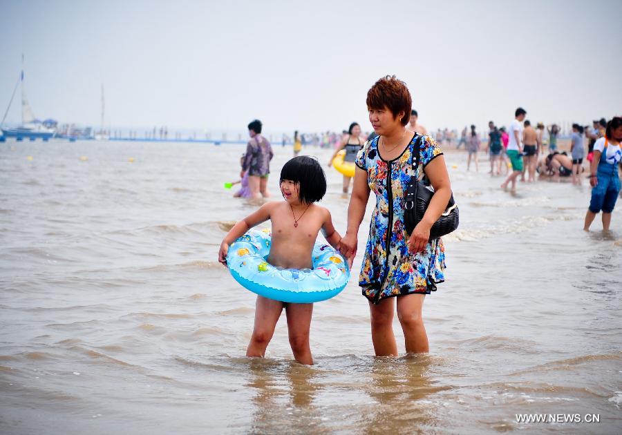 A woman takes her child to play along the bathing beach in Dongjiangwan of north China's Tianjin Municipality, June 30, 2013. Many people came to Dongjiangwan to spend their weekends. (Xinhua/Zhang Chaoqun) 