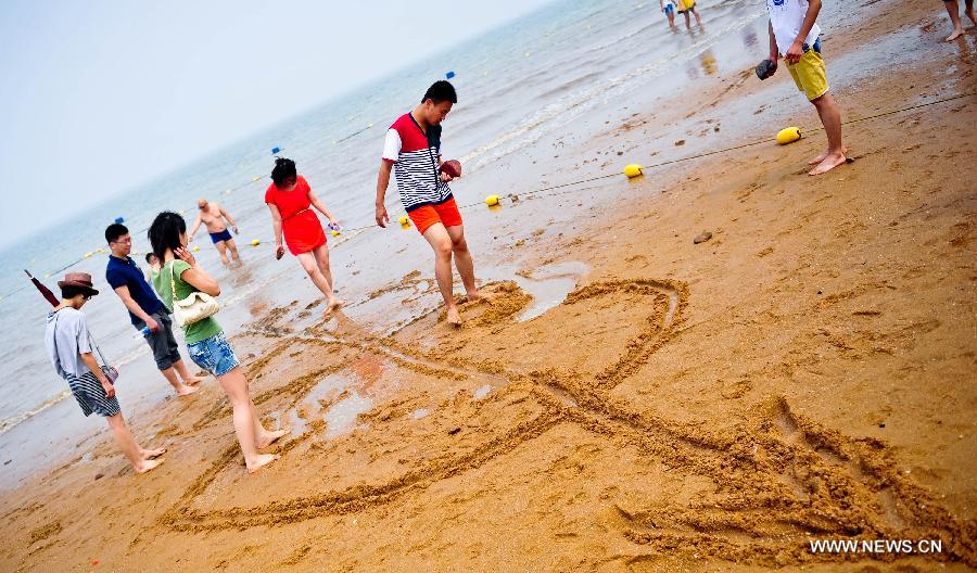 People make sand drawings on the bathing beach in Dongjiangwan of north China's Tianjin Municipality, June 30, 2013. Many people came to Dongjiangwan to spend their weekends. (Xinhua/Zhang Chaoqun)
