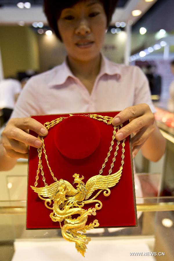 A staff member shows a gold necklace at the wedding expo in Beijing, capital of China, June 28, 2013. The three-day 2013 China (summer) wedding expo kicked off here on Friday. Some 3,000 exhibitors from over 30 countries and regions participated in the exposition. (Xinhua/Zhao Bing) 