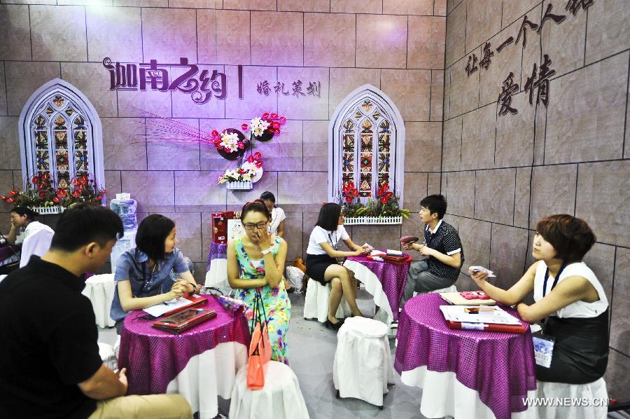 Visitors are seen at an exhibition booth at the wedding expo in Beijing, capital of China, June 28, 2013. The three-day 2013 China (summer) wedding expo kicked off here on Friday. Some 3,000 exhibitors from over 30 countries and regions participated in the exposition. (Xinhua/Wang Jingsheng) 