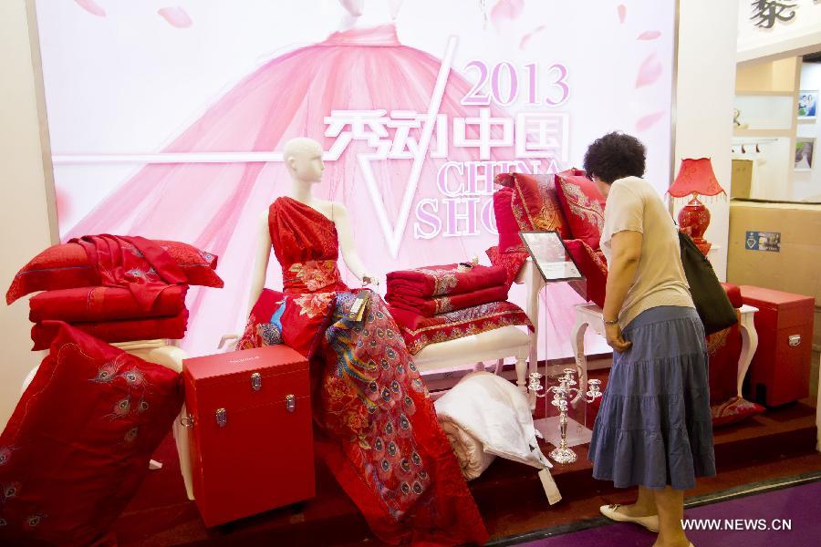A visitor looks at the wedding bedclothing at the wedding expo in Beijing, capital of China, June 28, 2013. The three-day 2013 China (summer) wedding expo kicked off here on Friday. Some 3,000 exhibitors from over 30 countries and regions participated in the exposition. (Xinhua/Zhao Bing) 