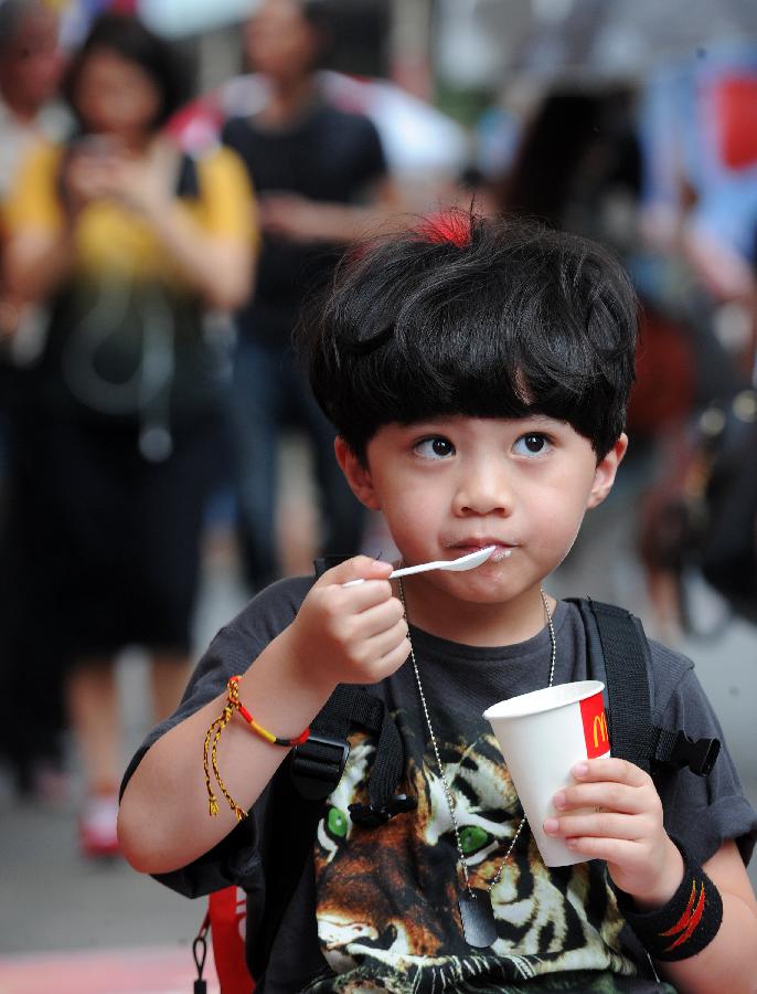 A kid eats ice cream under tree shade in Taipei, southeast China's Taiwan, June 30, 2013. Taiwan's weather bureau announced Sunday that the average temperature in this June has reached 29 Celsius degree, a record high since Taipei weather station was established in 1896. (Xinhua/Tao Ming) 
