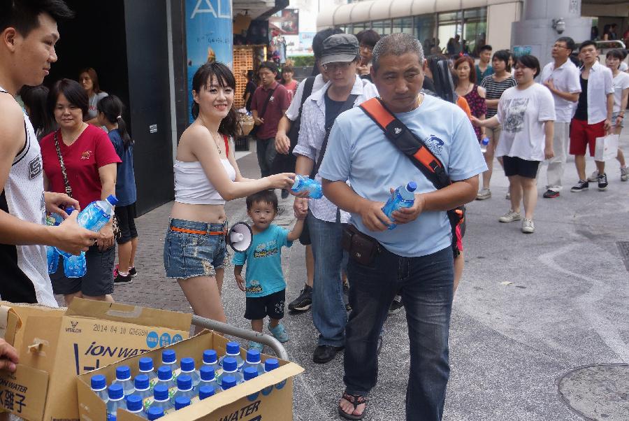 Staff members of a drinks producer send free cold drinks to people in Ximending, a busy commercial area in Taipei, southeast China's Taiwan, June 30, 2013. Taiwan's weather bureau announced Sunday that the average temperature in this June has reached 29 Celsius degree, a record high since Taipei weather station was established in 1896. (Xinhua/Tao Ming)