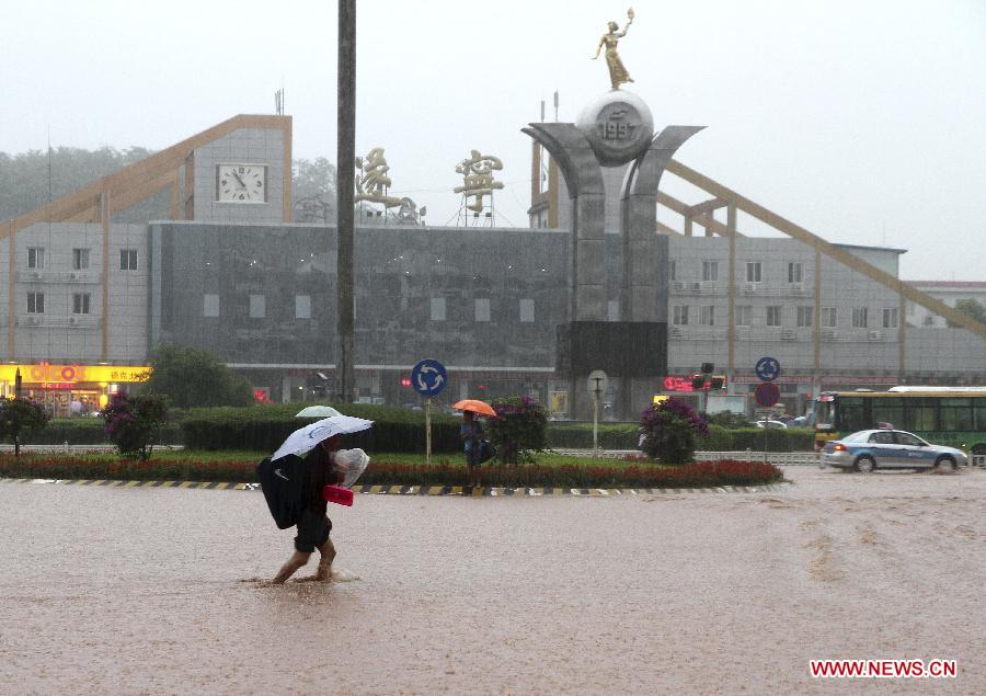 A citizen walks on a waterlogged street in the rain in Suining City, southwest China's Sichuan Province, June 30, 2013. Two people died and five others are missing in Sichuan Province after torrential rain triggered flooding and landslides in the region on Sunday, local authorities said. (Xinhua/Hu Ming) 