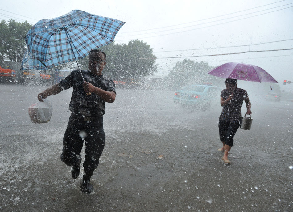Citizens walk on the waterlogged road in Nanjing, capital of east China's Jiangsu province, June 25, 2013. Heavy rainfall hit many parts of Jiangsu. (Xinhua)