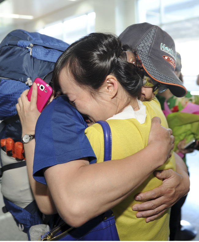 Zhang Jingchuan, a mountaineer who survived a terrorist attack in Pakistan's northern Gilgit-Baltistan area, hugs his wife on June 25, 2013 at Urumqi International Airport, in Xinjiang Uygur autonomous region. (Photo/Xinhua)