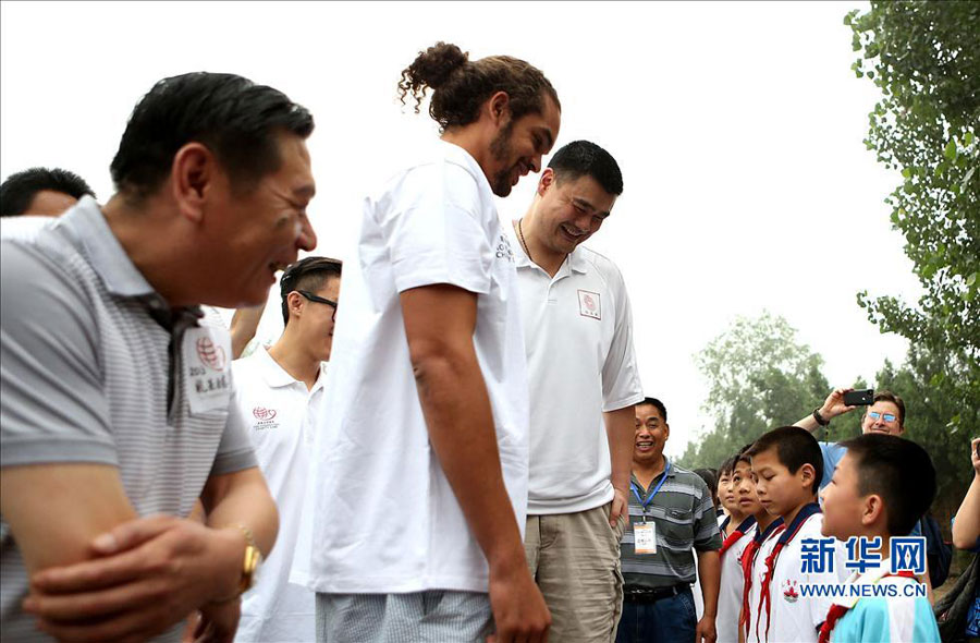 Former NBA star Yao Ming and Joakim Noah of Chicago Bulls talk with students during their visit to a primary school for children from migrant workers' families in Changping district in the northern suburbs of Beijing, Sunday, June 30, 2013. The visit is part of the Yao Foundation charity events in 2013, which inlcude a charity basketball game on July 1, 2013 in MasterCard Center in Beijing.