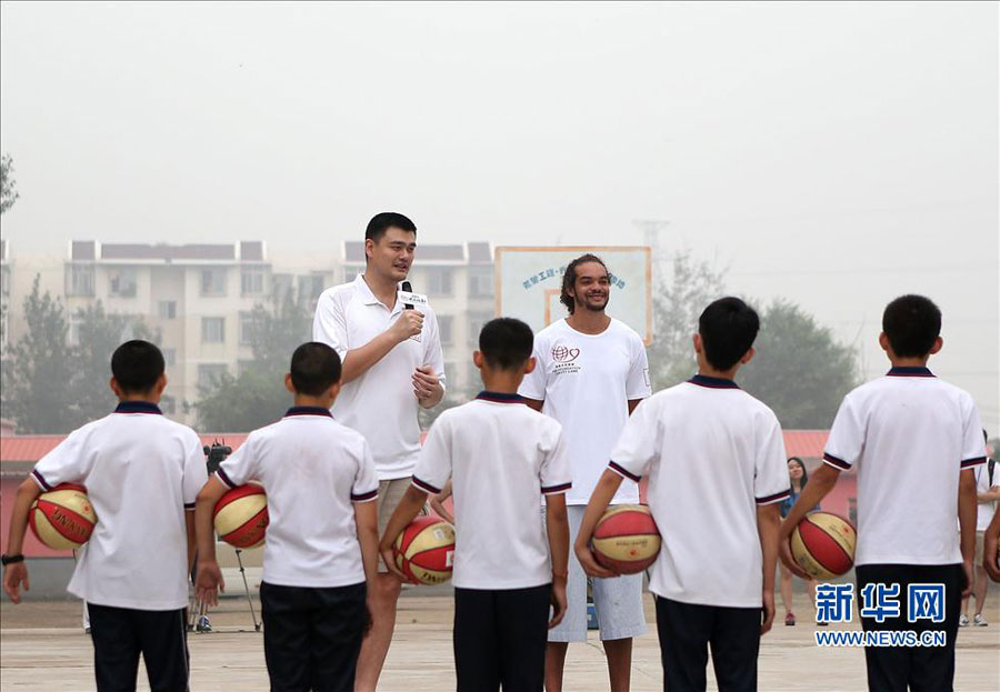 Former NBA star Yao Ming and Joakim Noah of Chicago Bulls talk with students during their visit to a primary school for children from migrant workers' families in Changping district in the northern suburbs of Beijing, Sunday, June 30, 2013. The visit is part of the Yao Foundation charity events in 2013, which inlcude a charity basketball game on July 1, 2013 in MasterCard Center in Beijing.