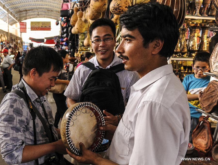 Tourists buy folk musical instruments at Kashi Grand Bazzar in Kashi Prefecture, northwest China's Xinjiang Uygur Autonomous Region, June 30, 2013. Kashi Grand Bazzar is the largest international business market in China's northwest region. Bazzar in Uygur language means market or fair. (Xinhua/Shen Qiao)