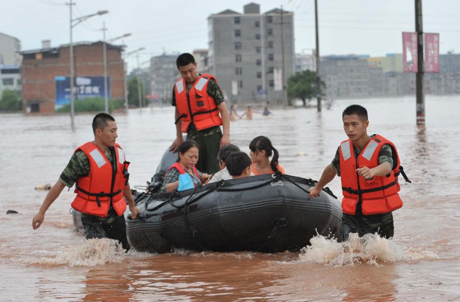 Firemen help evacuate residents at Baizi Town in Tongnan County of Chongqing, southwest China's municipality, July 1, 2013. Rainstorms swept the county Sunday, flooding low-lying area and forcing the evacuation of some 18,000 people. (Xinhua/Liu Chan) 