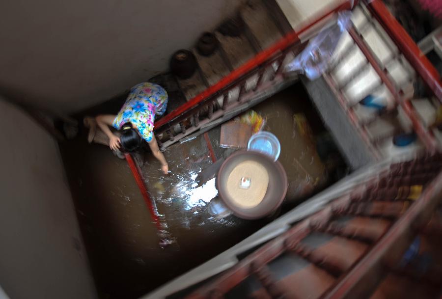 A resident salvages articles at a flooded building at Baizi Town in Tongnan County of Chongqing, southwest China's municipality, July 1, 2013. Rainstorms swept the county Sunday, flooding low-lying area and forcing the evacuation of some 18,000 people. (Xinhua/Liu Chan) 