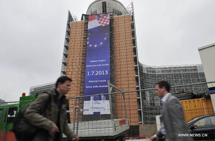 Pedestrians walk past a giant banner hanging outside the European Commission building to celebrate Croatia's entry into the European Union in Brussels, capital of Belgium, July 1, 2013. Croatia became the 28th member of the European Union on Monday. (Xinhua/Ye Pingfan)