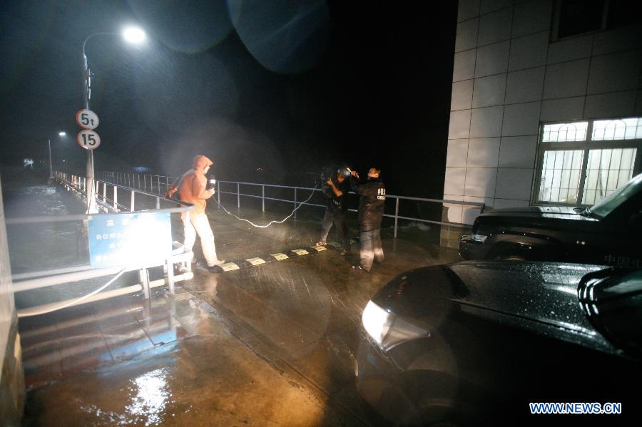 Journalists cover the tropical storm at a dock when tropical storm Rumbia lands on Zhanjiang, south China's Guangdong Province, July 2, 2013. Tropical storm Rumbia landed on Zhenjiang on Tuesday morning and brought torrential rain and gales to some areas in Guangdong Province. (Xinhua/Liang Zhiwei)