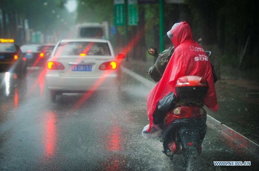 People ride in rain in Changchun, capital of northeast China's Jilin Province, July 2, 2013. Heavy rain has hit Jilin in recent days. (Xinhua/Xu Chang)