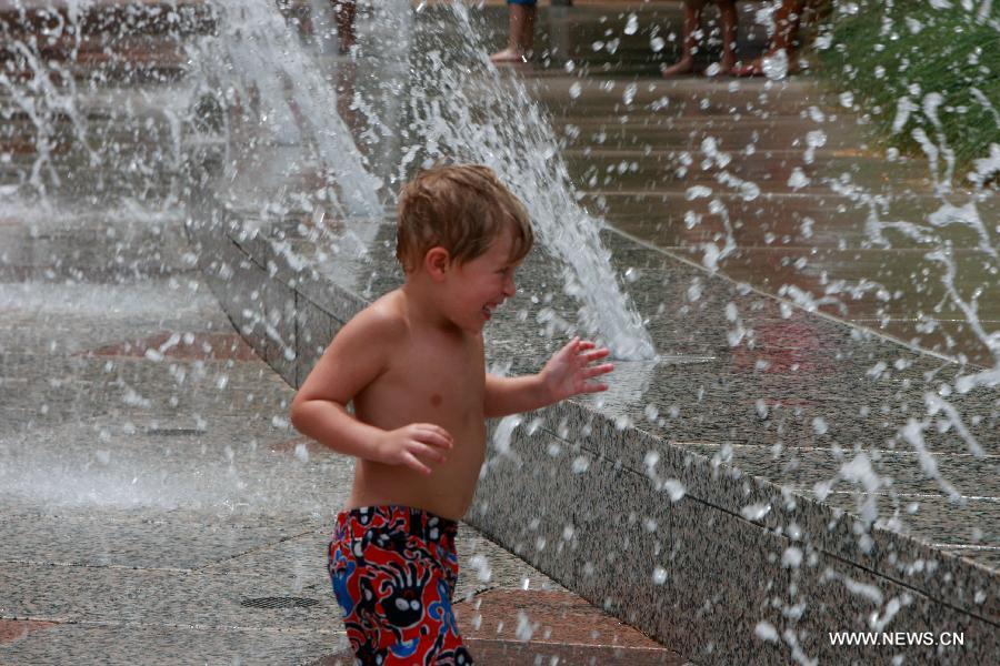 A kid plays water from a fountain at a park in central Houston, the United States on July 1, 2013. The temperature in Houston has been high in recent days. (Xinhua/Song Qiong)