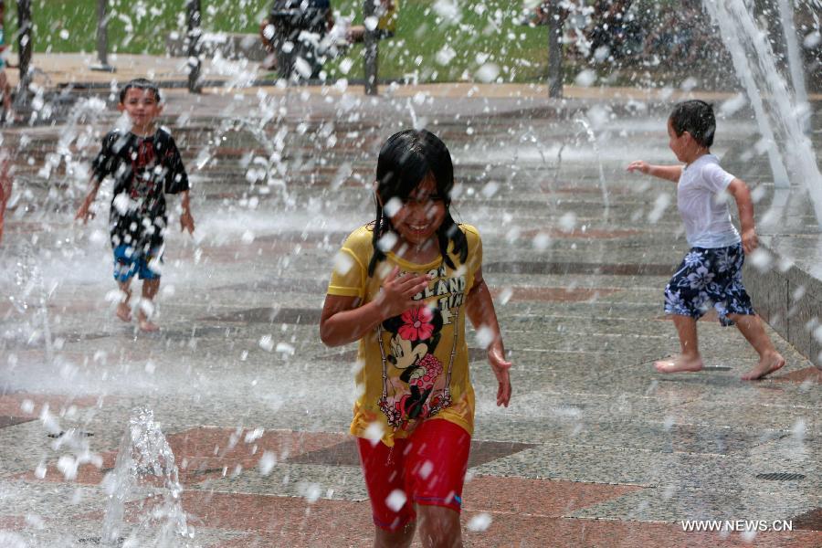 Kids play water from a fountain at a park in central Houston, the United States on July 1, 2013. The temperature in Houston has been high in recent days. (Xinhua/Song Qiong)