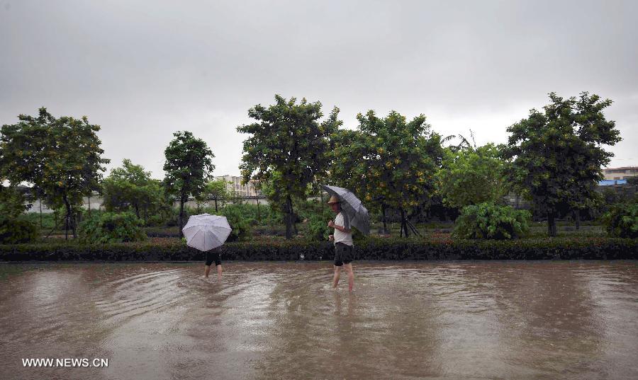Pedestrians walk on a flooded road in Beihai, south China's Guangxi Zhuang Autonomous Region, July 2, 2013. Strong tropical storm Rumbia entered into Guangxi on Tuesday. (Xinhua/Huang Xiaobang)