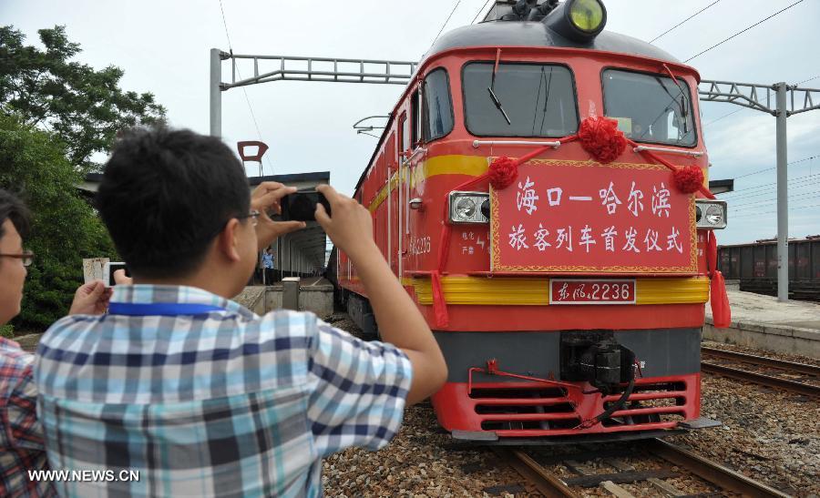 Passengers take photos of the locomotive of the first direct train from Haikou to Harbin at Haikou Railway Station in Haikou, capital of south China's Hainan Province, July 2, 2013. The train K1122/3 from south China's Haikou to northeast China's Heilongjiang left Haikou Tuesday, a day later than its original departure date due to the tropical storm Rumbia. The train which travels 4,458 kilometers for 65 hours has connected China's southernmost capital city Haikou of Hainan Province with China's northernmost capital city Harbin of Heilongjiang Province. (Xinhua/Zhao Yingquan)