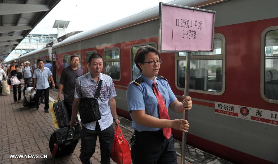 A staff member guides the passengers to aboard the first direct train from Haikou to Harbin at the Haikou Railway Station in Haikou, capital of south China's Hainan Province, July 2, 2013. The train K1122/3 from south China's Haikou to northeast China's Heilongjiang left Haikou Tuesday, a day later than its original departure date due to the tropical storm Rumbia. The train which travels 4,458 kilometers for 65 hours has connected China's southernmost capital city Haikou of Hainan Province with China's northernmost capital city Harbin of Heilongjiang Province. (Xinhua/Zhao Yingquan)