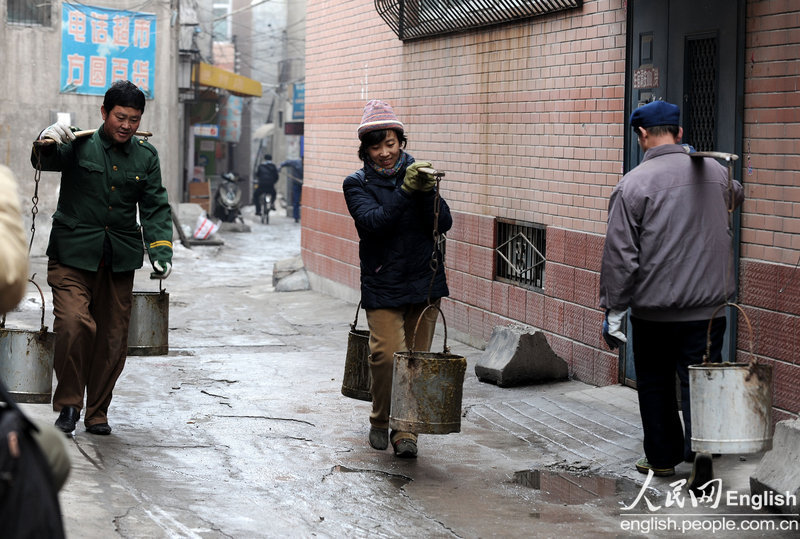 Zhang Ting, one of the five college students who signed contracts to become public toilet cleaners, carries a bucket of manure from toilet on March 3, 2010. (Photo/ CFP)