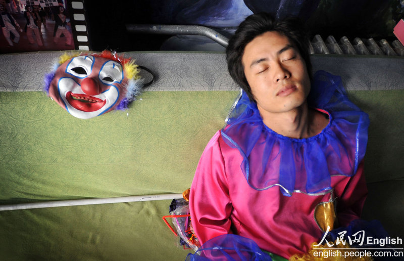 Yang Zhibing sleeps on a couch after busy work in Qingdao, Shandong province on Sept. 27, 2011. After graduation, 22-year-old Yang Zhibin and his classmates operated a creative company. He dresses up as a clown to send flowers and cake to clients; behind joy is hardship and sweat.  (Photo/CFP)