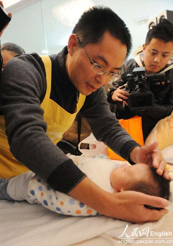 Li Dabin shows how to comfort a baby at a hospital in Changsha.  He is the first male confinement nurse with master degree.  (Photo/CFP)