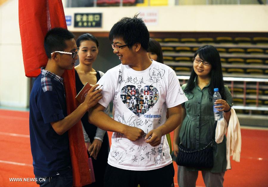 Zhang Guoqi (C), a graduate of the Taiyuan University of Technology, asks his classmate to sign on his T-shirt in the campus in Taiyuan, capital of north China's Shanxi Province, July 2, 2013. The Taiyuan University of Technology held a graduation ceremony for its more than 5,800 graduates on Tuesday. (Xinhua/Yan Yan)