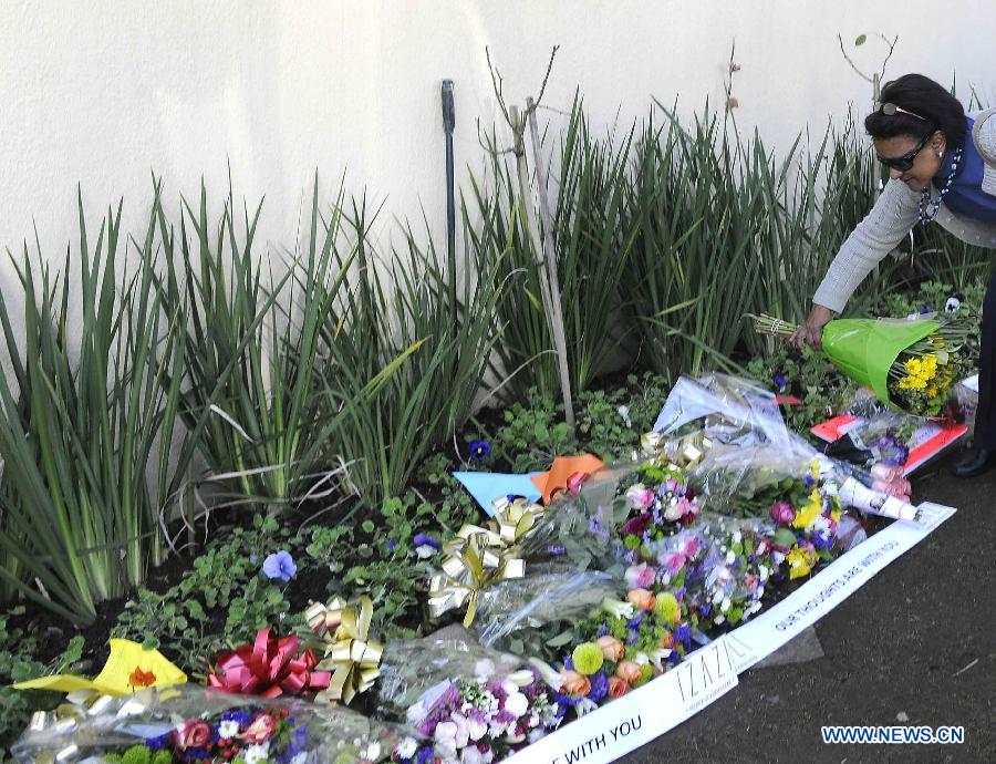 A resident presents flowers outside Nelson Mandela's house in Johannesburg, South Africa, on July 2, 2013. South Africans are ready to celebrate the 95th birthday of anti-apartheid icon Nelson Mandela who has been hospitalized for more than three weeks for a recurring lung infection, President Jacob Zuma said. Zuma said Mandela "is still critical but stable" in a Pretoria hospital where he was admitted on June 8. (Xinhua/Li Qihua)