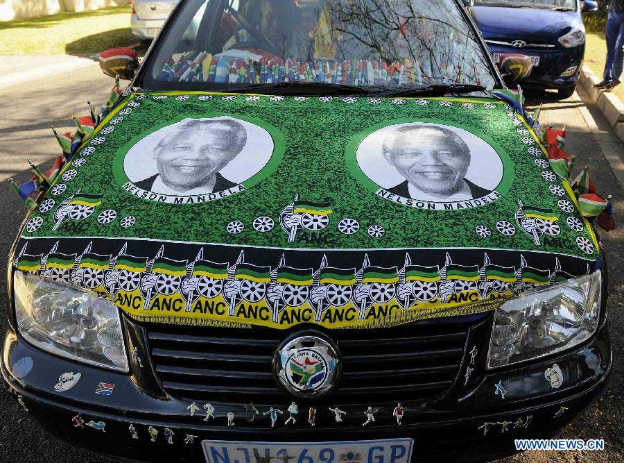 A resident drives a car decorated with Nelson Mandela's portraits outside Mandela's house in Johannesburg, South Africa, on July 2, 2013. South Africans are ready to celebrate the 95th birthday of anti-apartheid icon Nelson Mandela who has been hospitalized for more than three weeks for a recurring lung infection, President Jacob Zuma said. Zuma said Mandela "is still critical but stable" in a Pretoria hospital where he was admitted on June 8. (Xinhua/Li Qihua)