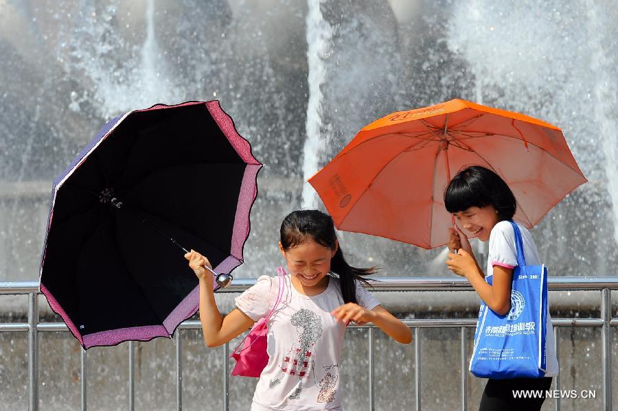 Children play besides a fountain in Jinan, capital of east China's Shandong Province, July 3, 2013. The highest temperature in Jinan reached 38 degrees celsius on Wednesday. (Xinhua/Guo Xulei)