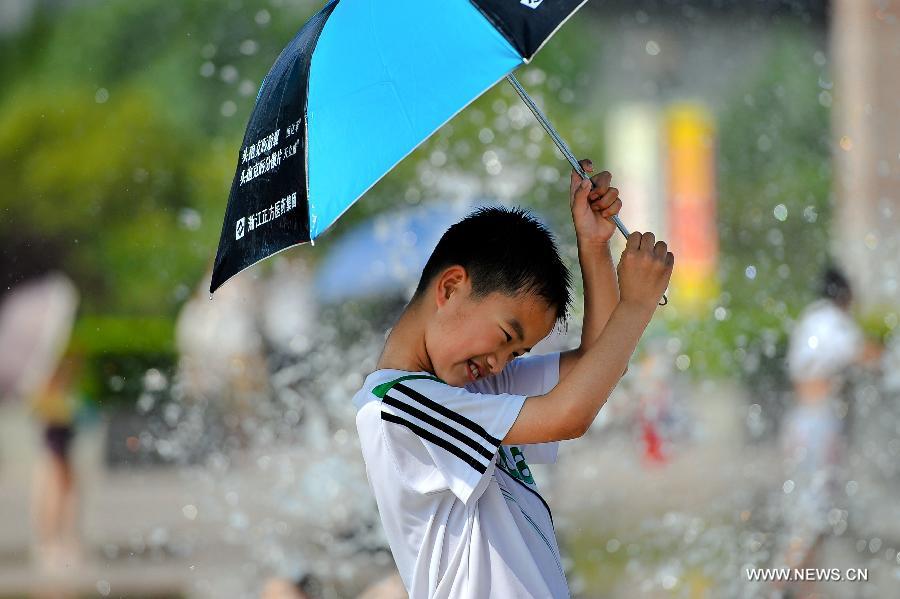 A child plays besides a fountain in Jinan, capital of east China's Shandong Province, July 3, 2013. The highest temperature in Jinan reached 38 degrees celsius on Wednesday. (Xinhua/Guo Xulei)