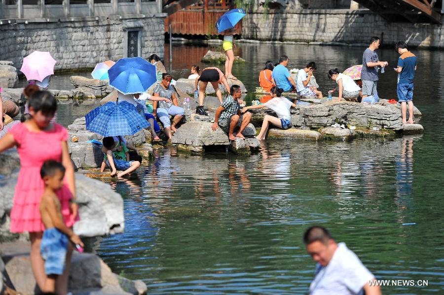 Citizens enjoy coolness at the riverside in Jinan, capital of east China's Shandong Province, July 3, 2013. The highest temperature in Jinan reached 38 degrees celsius on Wednesday. (Xinhua/Guo Xulei)