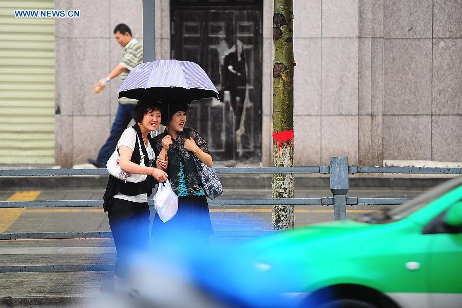 People wait for taxi in the rain in Xining, capital of northwest China's Qinghai Province, July 3, 2013. Xining was hit by rainfall in most parts of the city on Wednesday, which brought cool weather. (Xinhua/Li Shaopeng) 