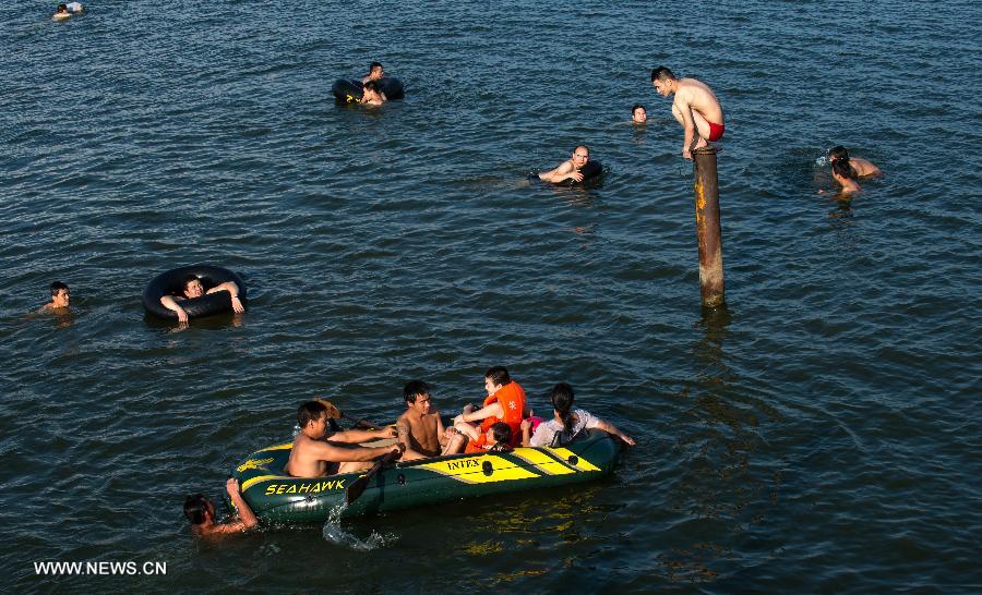 People enjoy coolness at the East Lake in Wuhan, capital of central China's Hubei Province, July 3, 2013. The highest temperature in Wuhan reached 36 degrees celsius on Wednesday. (Xinhua/Cheng Min)