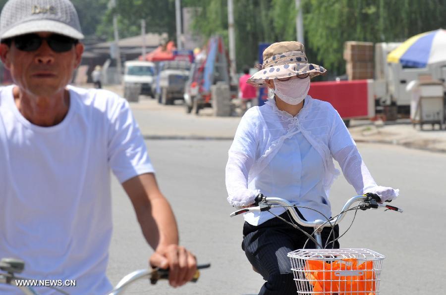 Citizens ride in the sun in Dingxing County, north China's Hebei Province, July 3, 2013. The highest temperatures in many parts of Hebei reached 37 degrees celsius on Wednesday. (Xinhua/Zhu Xudong)