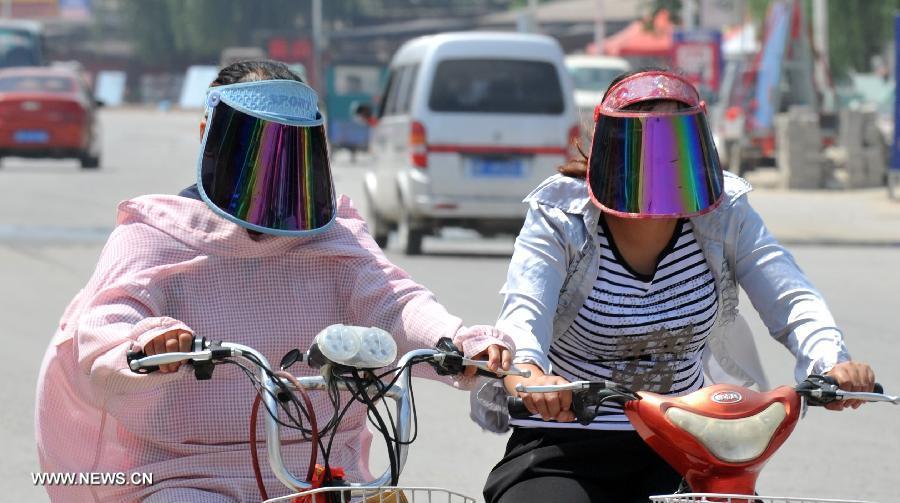 BAODING, July3, 2013 (Xinhua) -- Citizens wearing masks ride in Dingxing County, north China's Hebei Province, July 3, 2013. The highest temperatures in many parts of Hebei reached 37 degrees celsius on Wednesday. (Xinhua/Zhu Xudong)