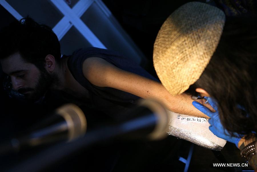 Chen Gong makes a tattoo on Juan Gonzalez Zamora's arm in Beijing, capital of China, July 2, 2013. (Xinhua/Zhang Chuanqi)
