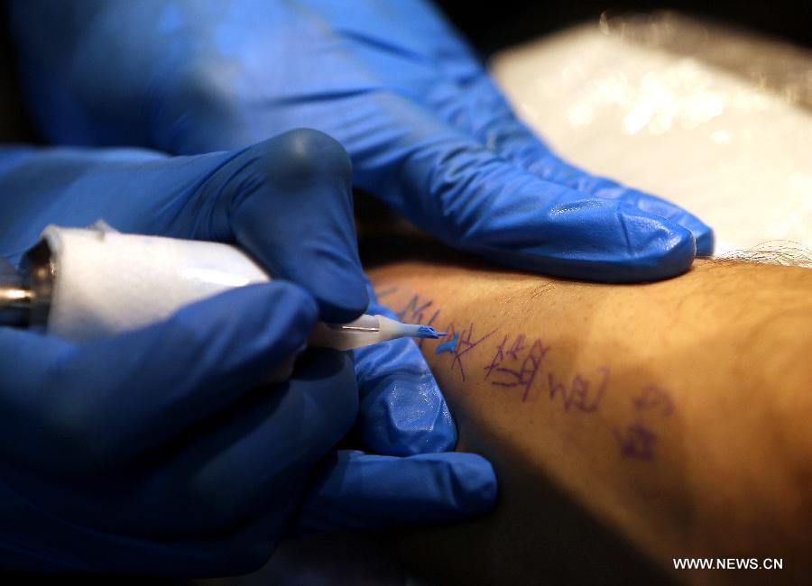 Chen Gong makes a tattoo on Juan Gonzalez Zamora's arm in Beijing, capital of China, July 2, 2013. (Xinhua/Zhang Chuanqi)