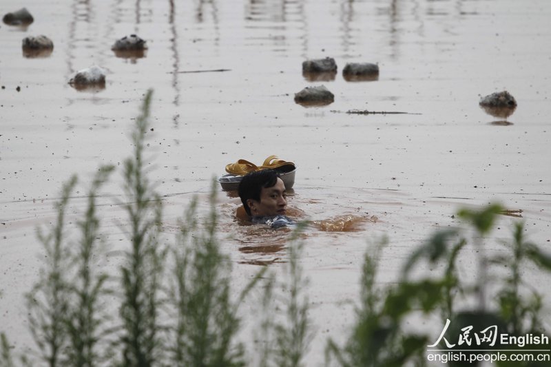 A man in Chongqing swam across a flooded river to fetch hot food for his pregnant wife trapped by rising floodwater.(Photo: CFP)