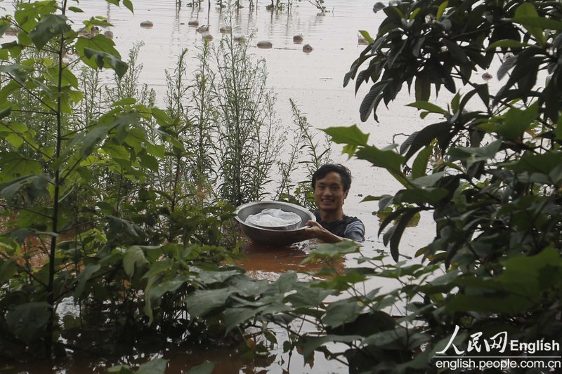 A man in Chongqing swam across a flooded river to fetch hot food for his pregnant wife trapped by rising floodwater.(Photo: CFP)