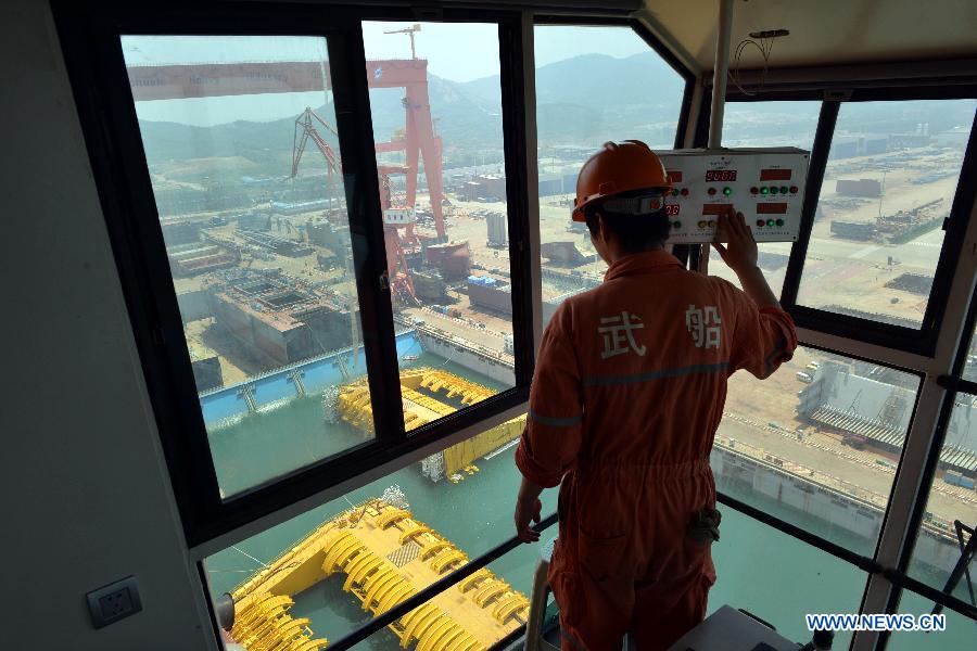 A worker operates a crane to lift the newly-built deep-sea engineering equipment in Qingdao, east China's Shandong Province, July 3, 2013. (Xinhua/Wan Houde)